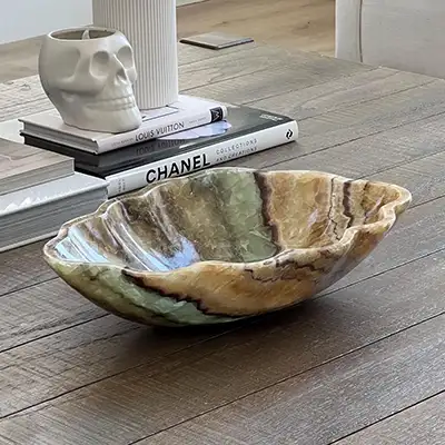 Natural onyx stone bowl with translucent veining used as a sculptural accent on a contemporary coffee table