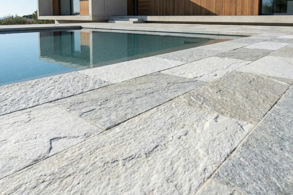 Natural quartzite outdoor pavers with flamed finish used around a modern luxury pool terrace, showcasing rugged texture, crystalline sparkle, and extreme durability under direct sunlight