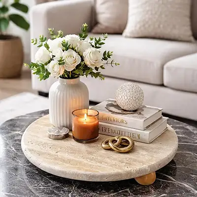 Natural travertine stone tray used as a sculptural surface on a marble coffee table in a contemporary living room